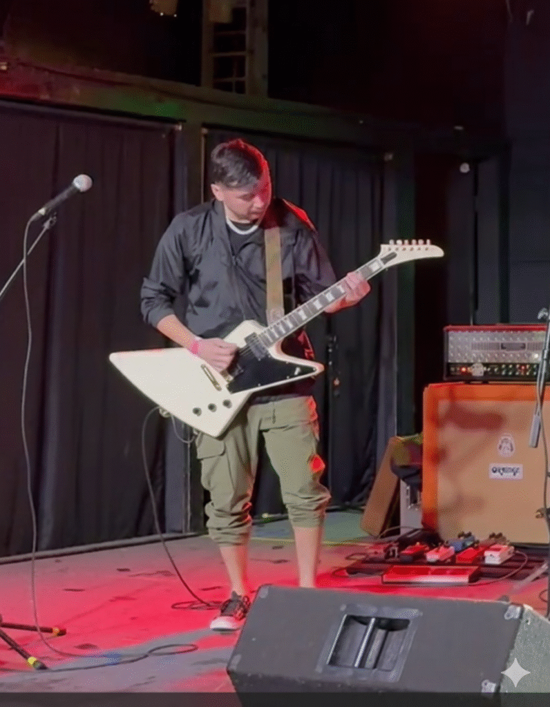Second Illusion guitarist performing live at BFE Rock Club under red and blue lighting, playing electric guitar during a rock concert.